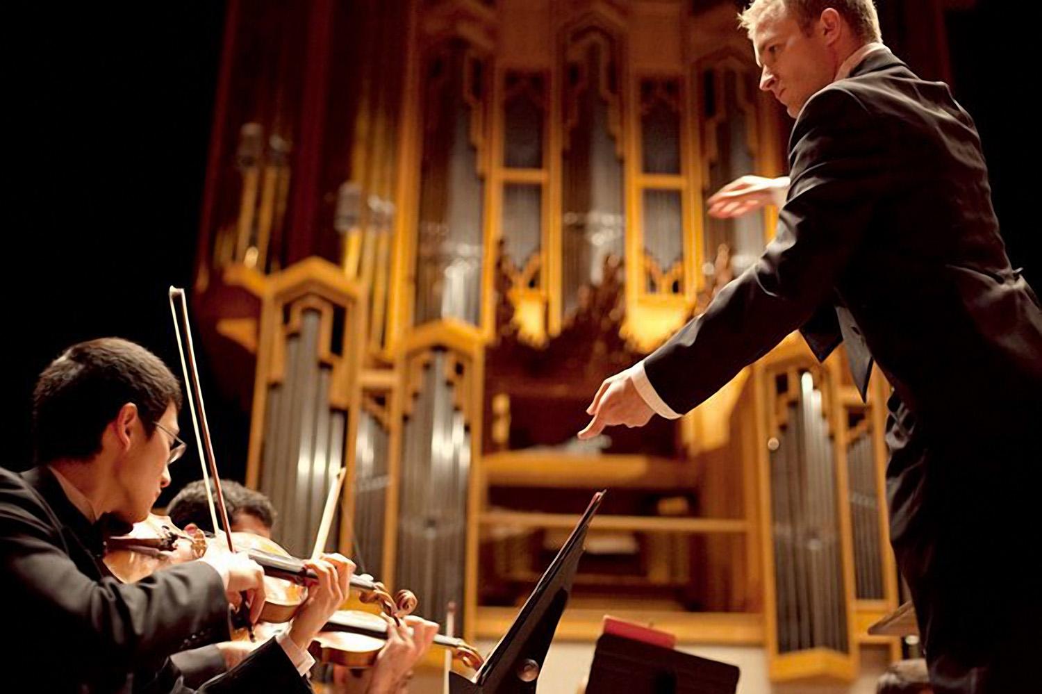 A Conductor conducts a chamber orchestra in Bates Recital Hall