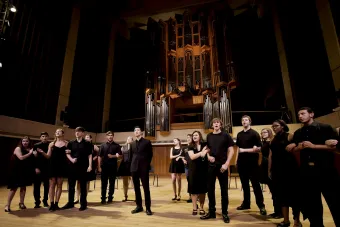 undergraduate opera students perform an opera scene on stage, dressed in black.