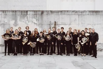 the 2019 horn studio with their horns, in a white stone courtyard.
