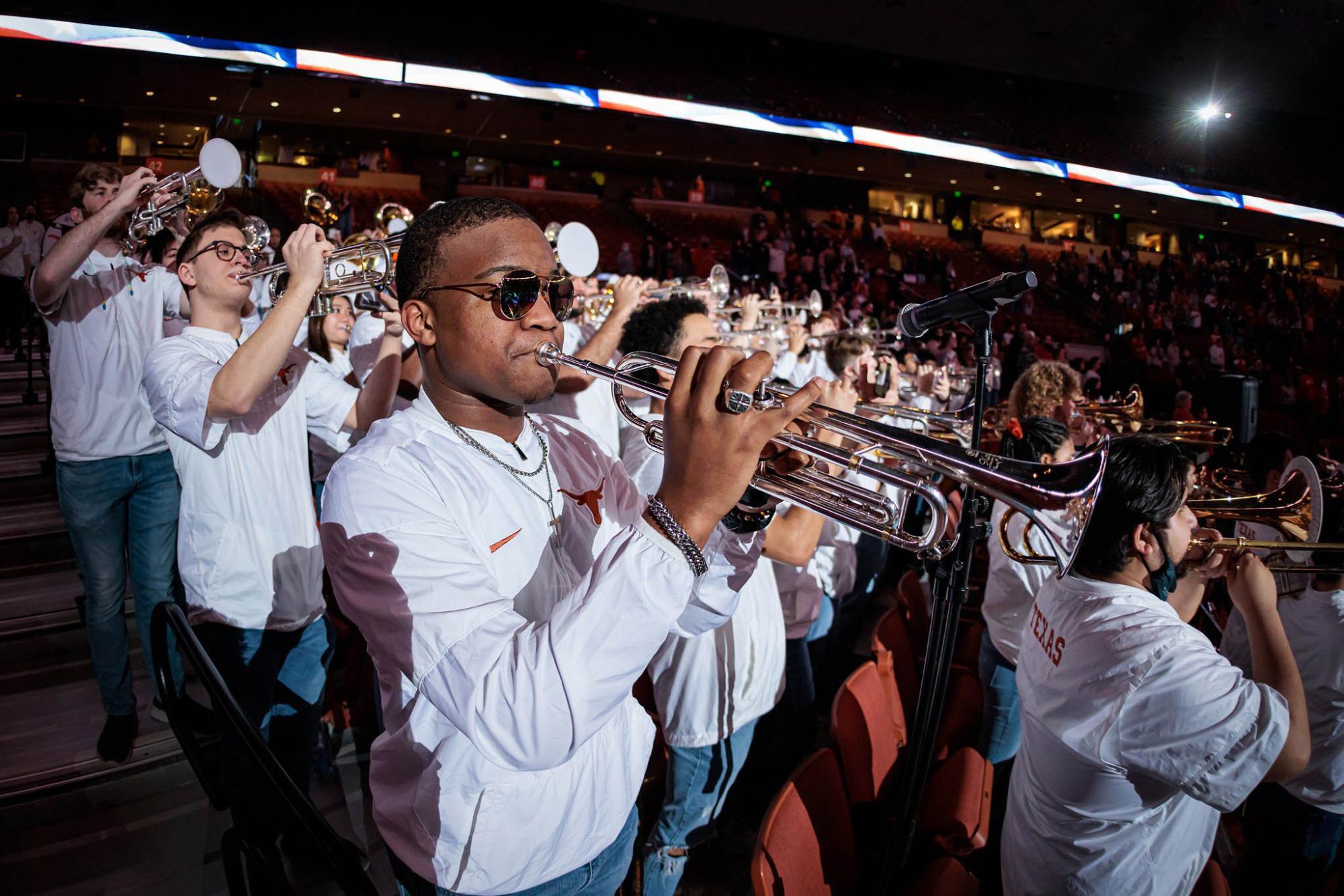 Pep band, standing and playing in the stands of the basketball arena